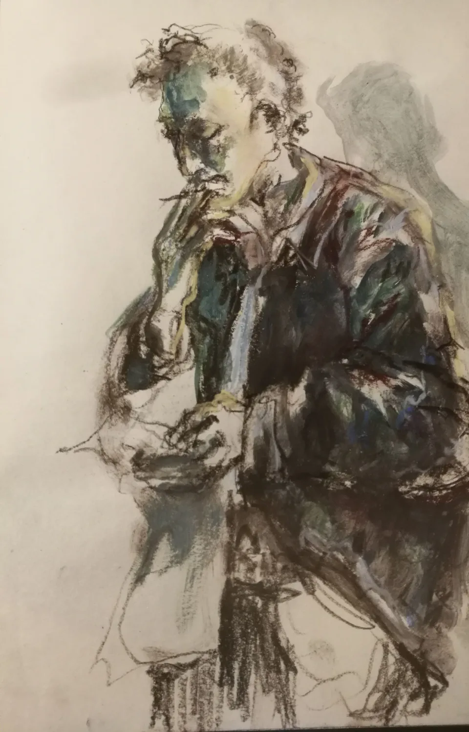 A standing figure in a long coat drawn in charcoal, one hand at the face