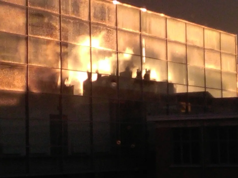 A long glass façade lit orange from within at dusk