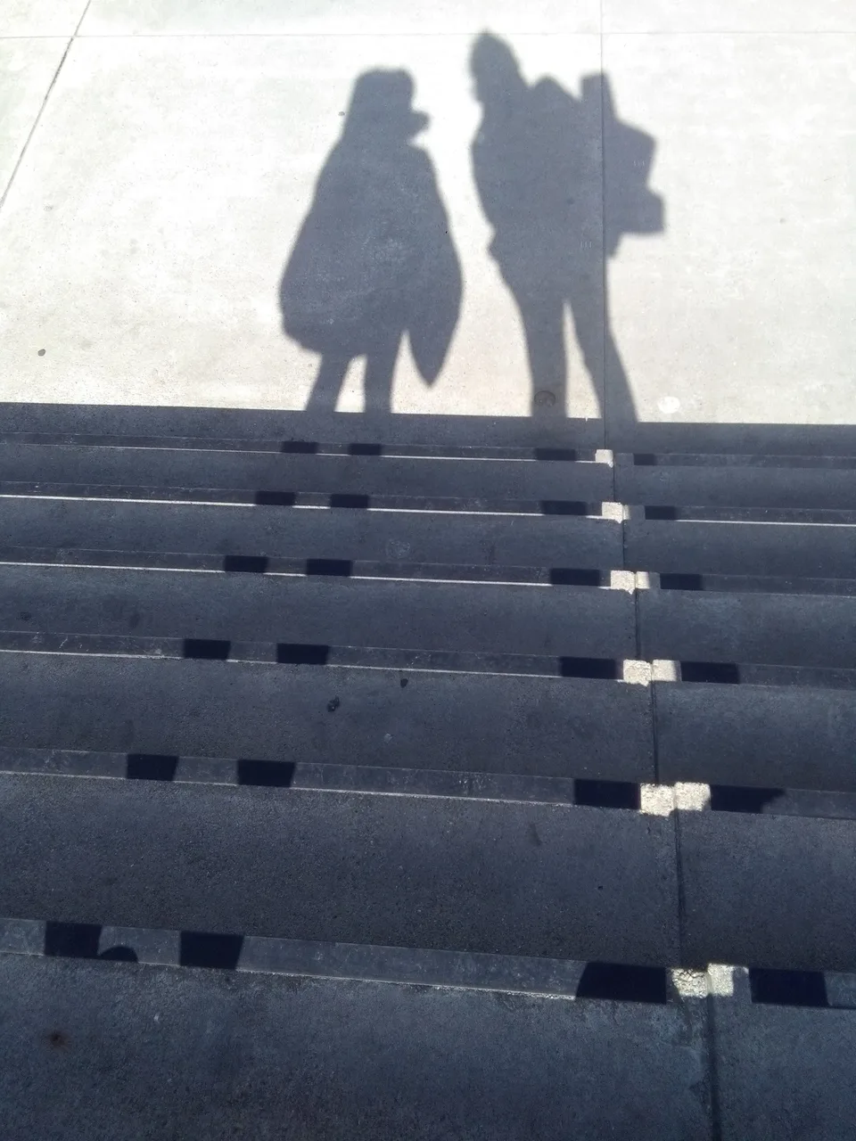 Two figures standing close together at the top of concrete steps in mist