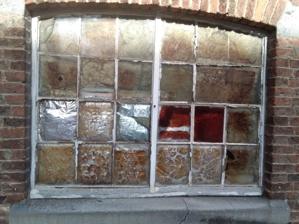An old metal-framed window of frosted amber and red panes