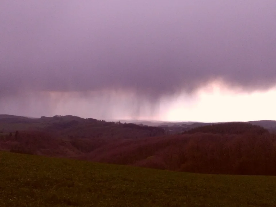 A violet storm sky low over dark hills