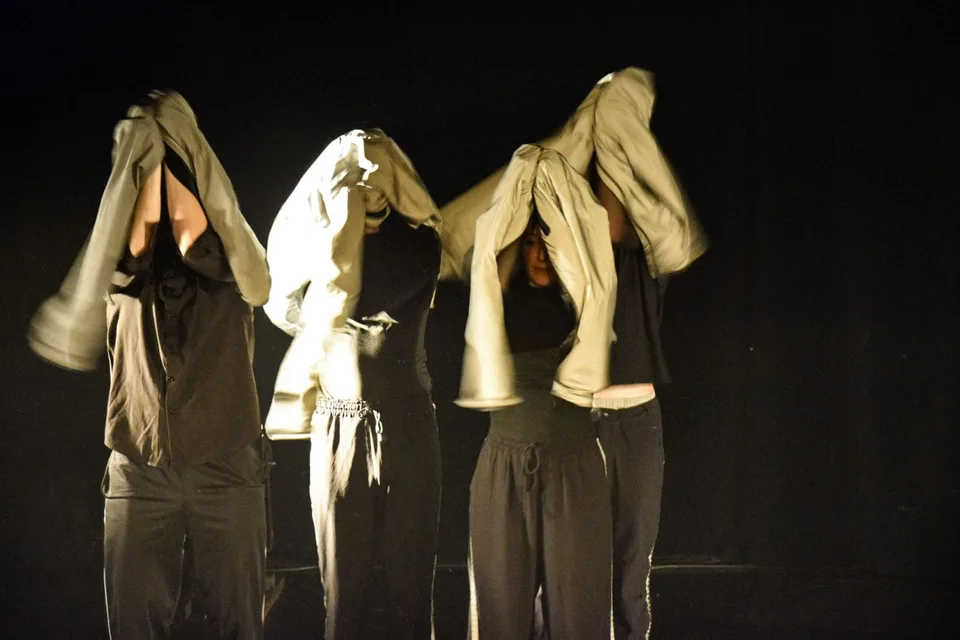 Three figures with pale cloth draped over their heads, lit gold