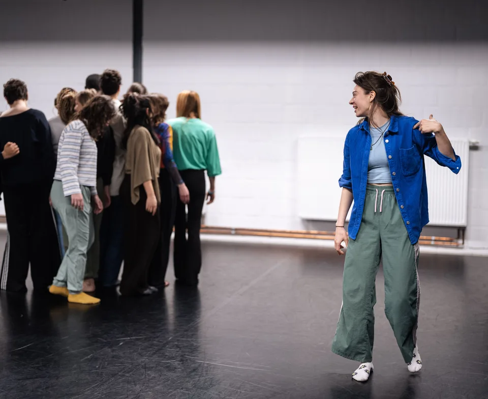 Elfine talking to a group gathered in a studio, one hand at her chest
