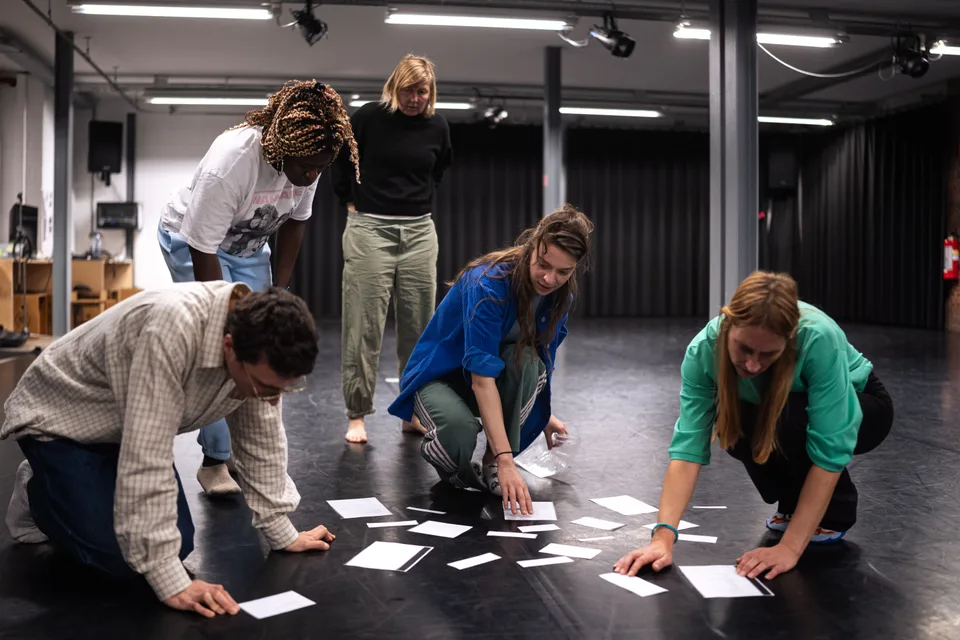 Participants kneeling on the studio floor, laying out white cards