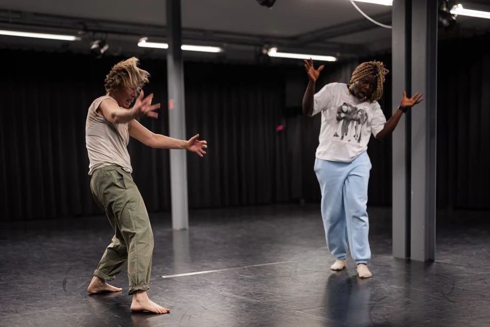 Two participants mid-movement across an empty studio floor